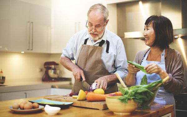 Men and women in a kitchen cooking healthy food